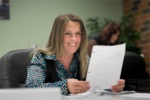 A woman holding a piece of paper smiles