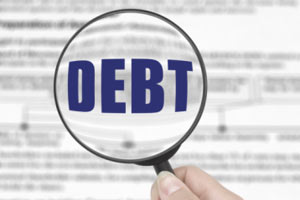 A magnifying glass with the word Debt enlarged