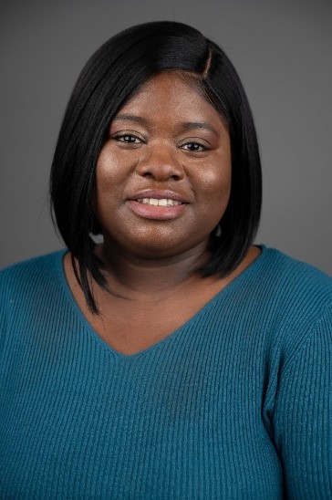 A headshot of a women with a short hair wearing a green top