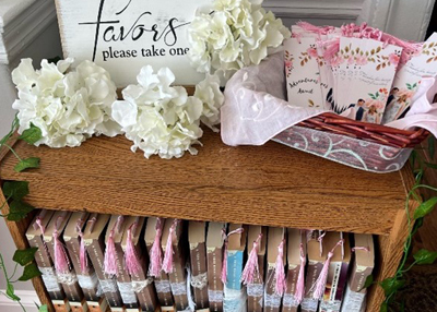 A picture of a small bookshelf full of books, a basket with bookmarkers, and a sign saying favors.