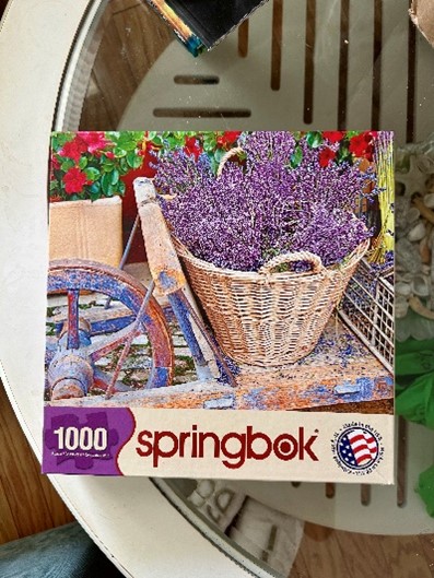 Box of a 1,000 Piece Puzzle showing a purple flower in a basket
