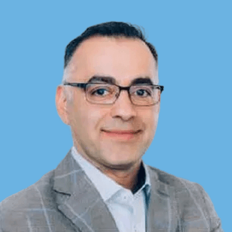 Professional portrait of a man in a gray suit with glasses against a blue background
