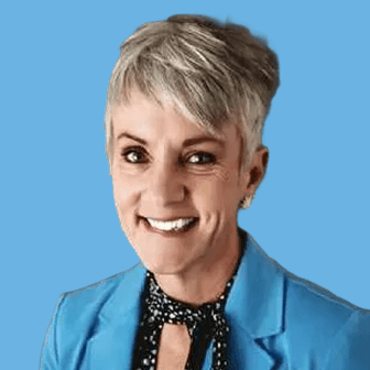 Smiling woman with short gray hair wearing a blue blazer against a blue background.