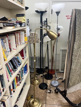 A standing lamp and books on a shelf in a storage room