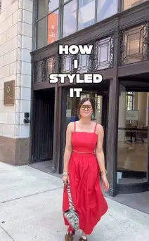 Women standing in front of a building wearing a long red dress holding a zebra purse