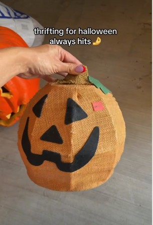 A hand holding a glowing jack-o'-lantern